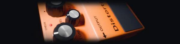 Pitch Suite Pro, DISTORT: an orange compact distortion pedal lying flat, plugged in